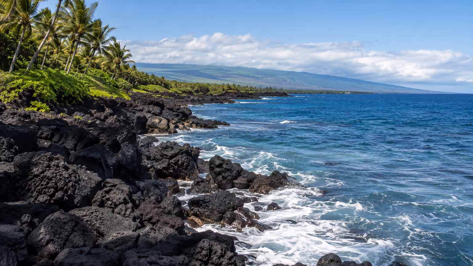 A black volcanic shoreline on Hawaii's Big Island with gentle Pacific waves