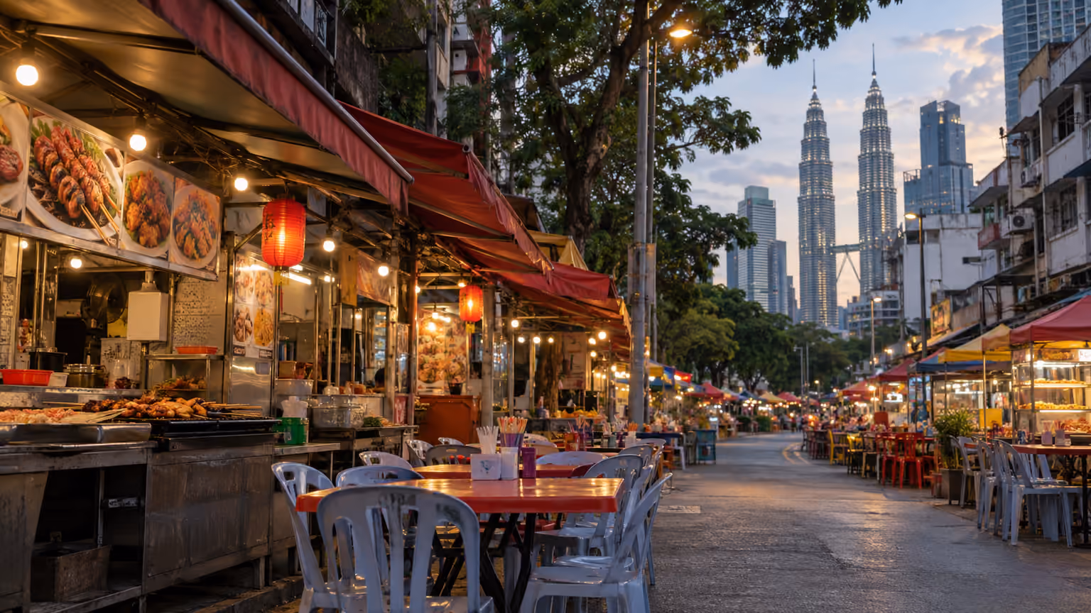 A Jalan Alor food-street setting in Kuala Lumpur with simple outdoor dining tables beneath
