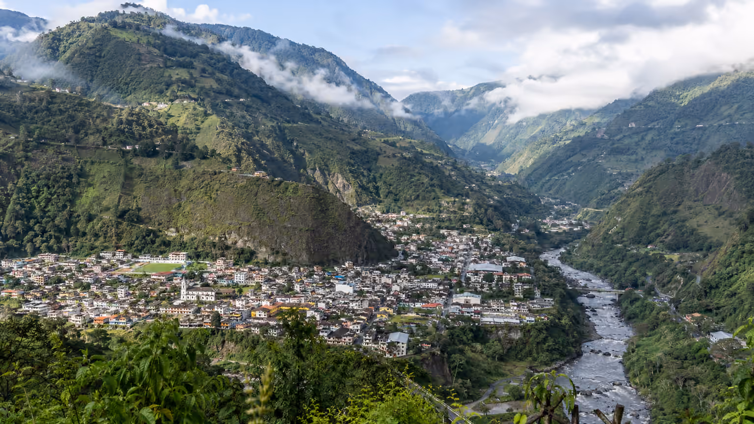 The green mountain valley around Banos Ecuador with cloud-softened slopes and a natural winding