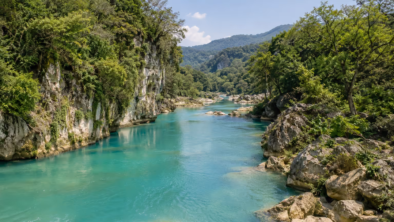 Turquoise Rio Tampaon flowing between limestone banks and green vegetation in the Huasteca