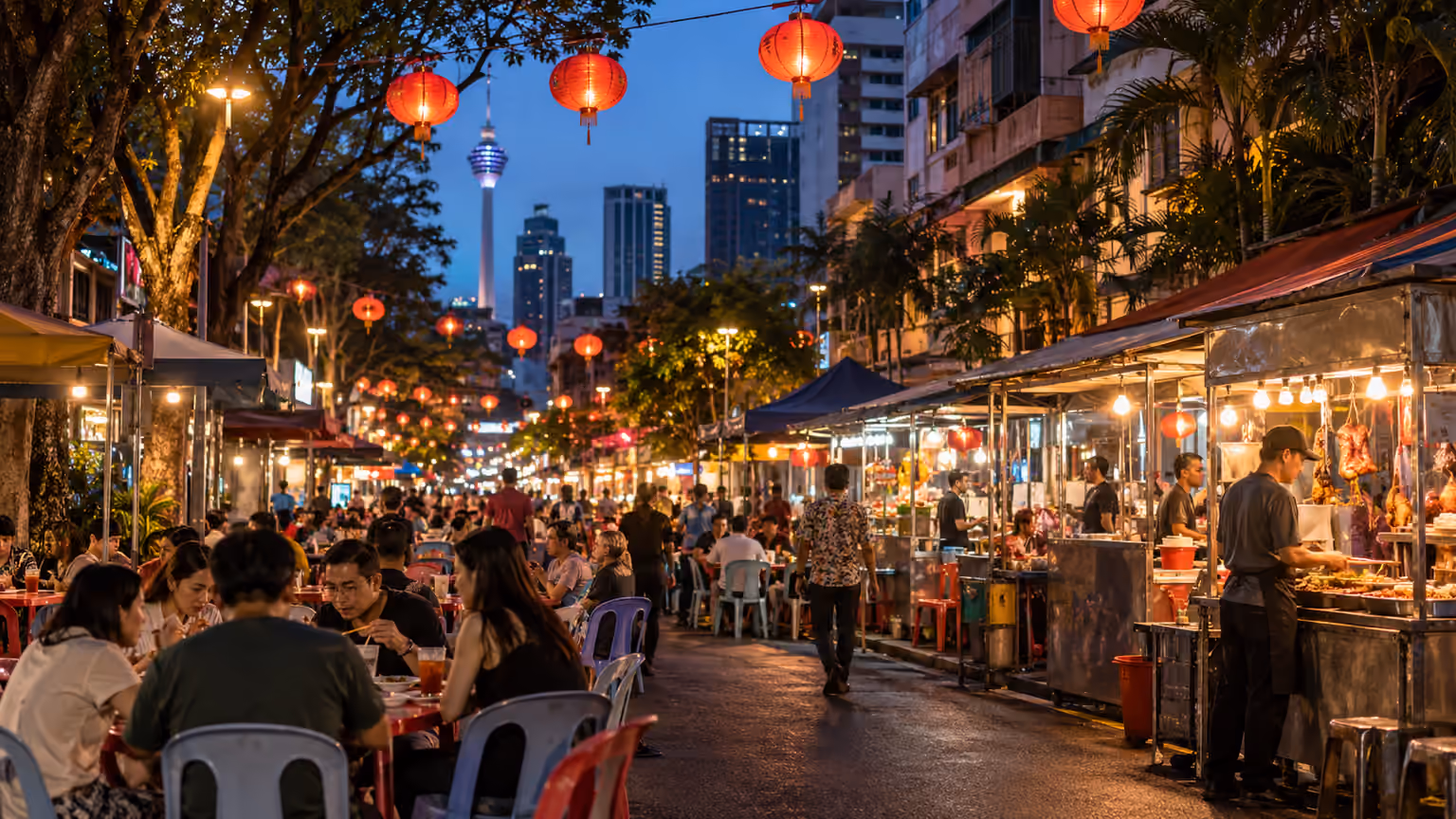 Lanterns and outdoor dining tables along a lively Kuala Lumpur food street at dusk