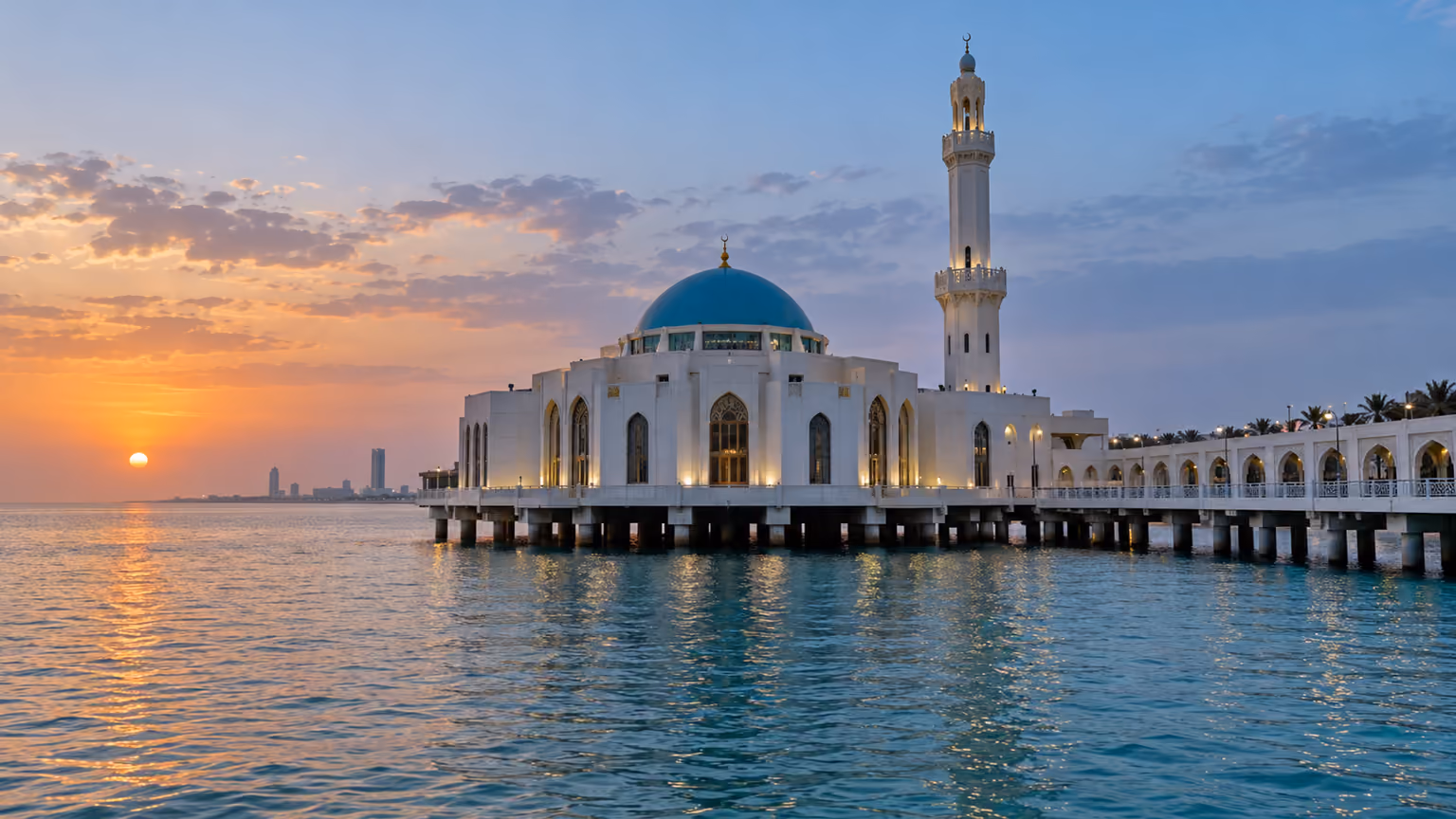 The white Al Rahma Mosque with a blue dome above Red Sea water at sunset in Jeddah