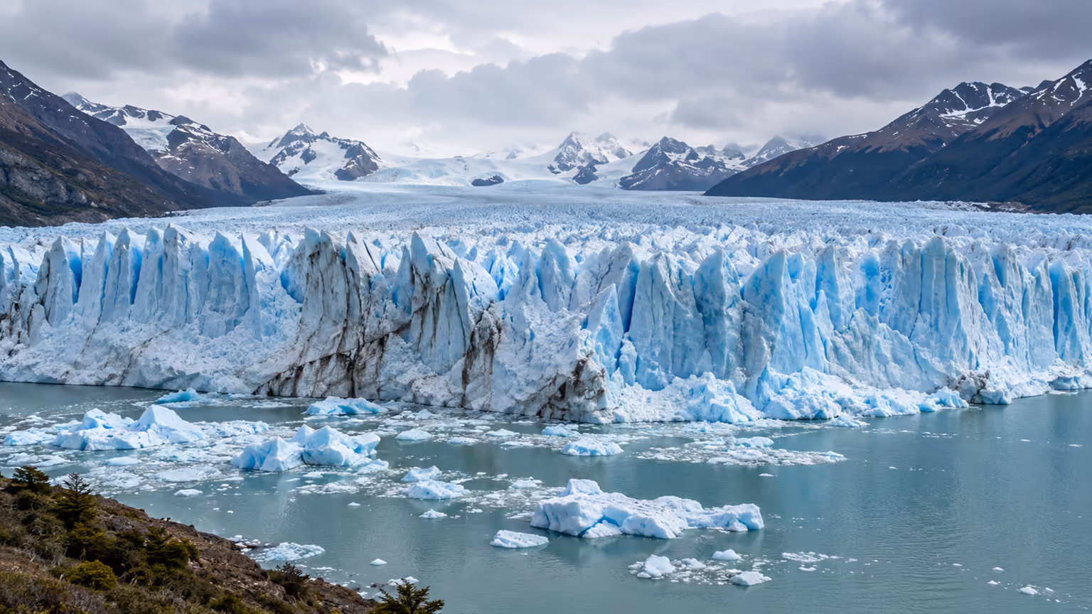 The blue ice wall of Perito Moreno Glacier rising above a Patagonian lake