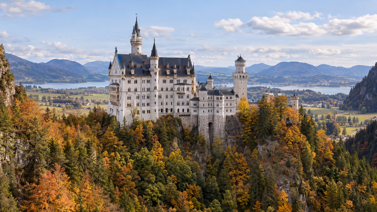 Neuschwanstein Castle rising above wooded hills and the Bavarian mountain landscape