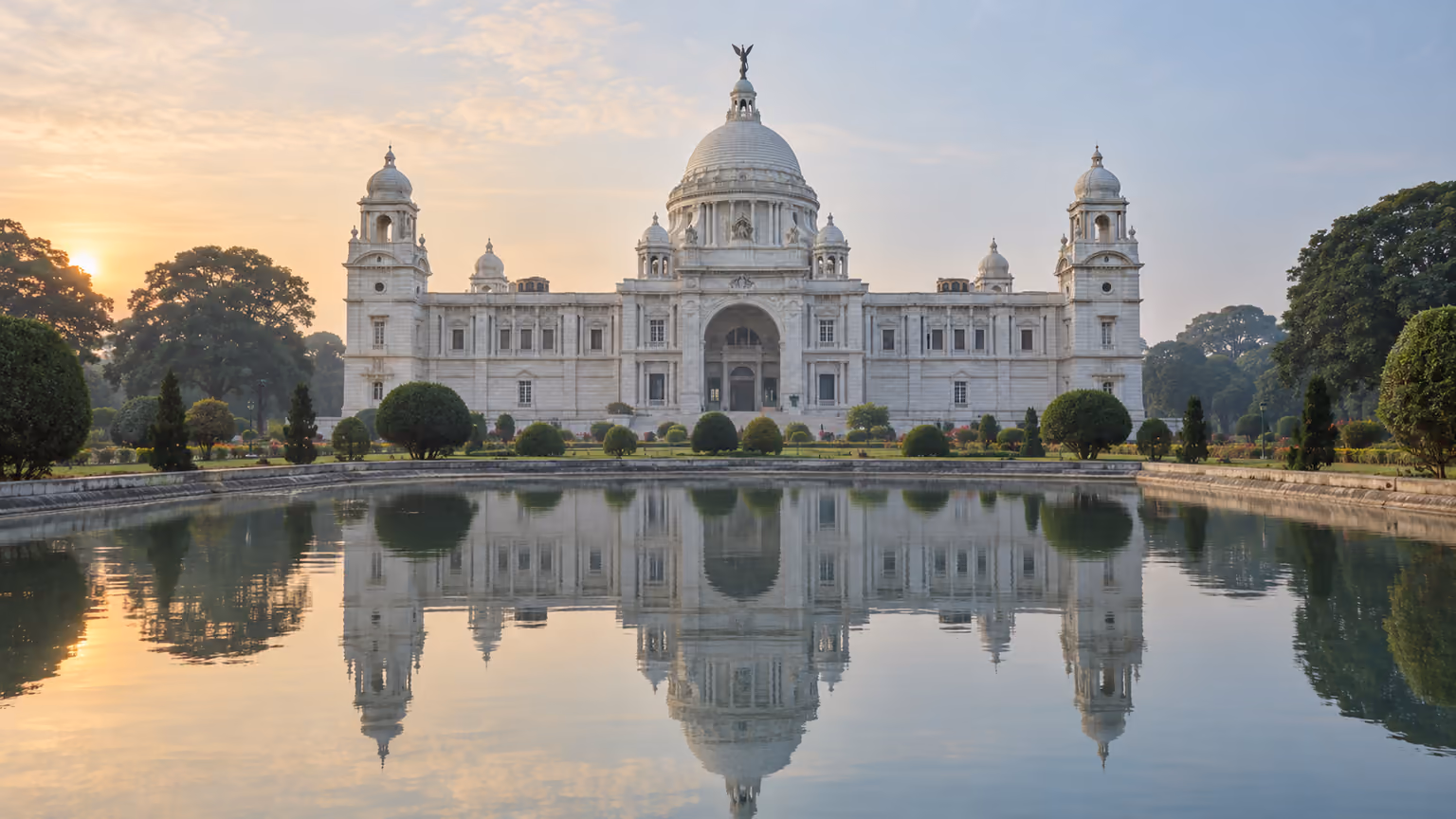 The white marble Victoria Memorial and its dome reflected in a garden pond in Kolkata